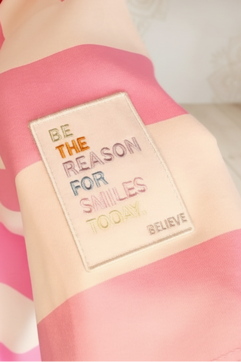 Rosa-weiß gestreifter Boho-Luxe Stoff mit buntem 'Be the reason for smiles today' Patch.