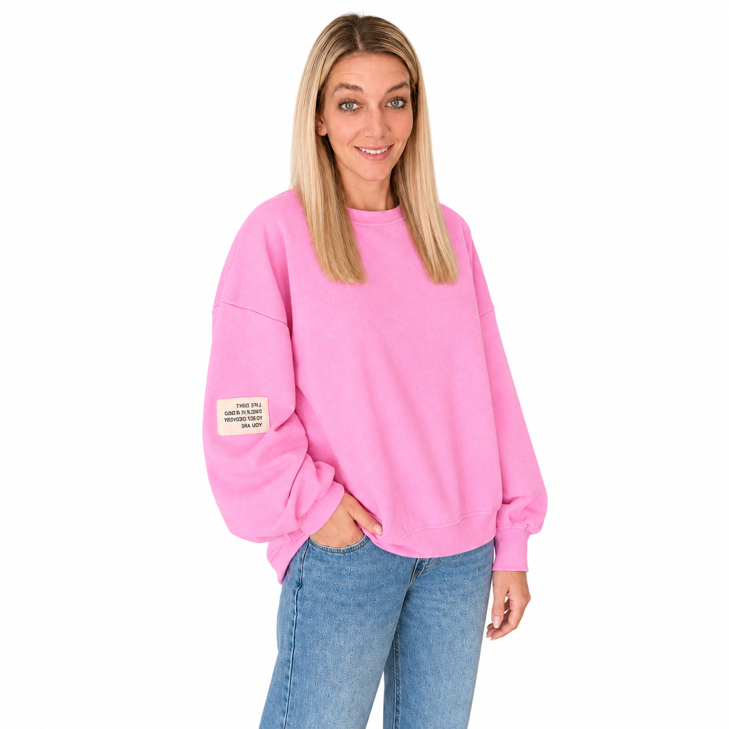 Pinkes Damen-Sweatshirt mit Rundhalsausschnitt, weiten langen Ärmeln und hellem Ärmelpatch, am Model zur blauen Jeans vor weißem Hintergrund.