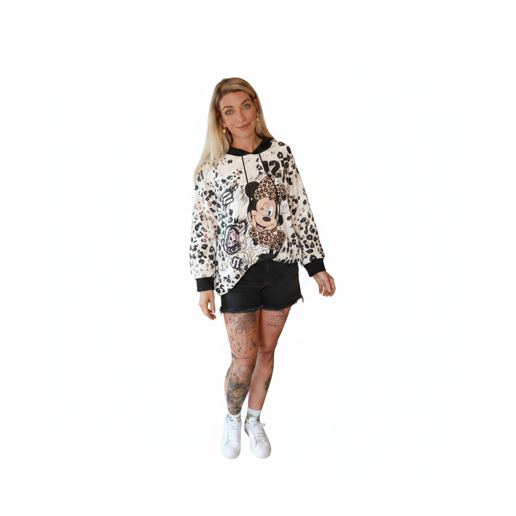 Frau in einem gemusterten Hoodie mit Minnie Maus Motiv und schwarzen Shorts.