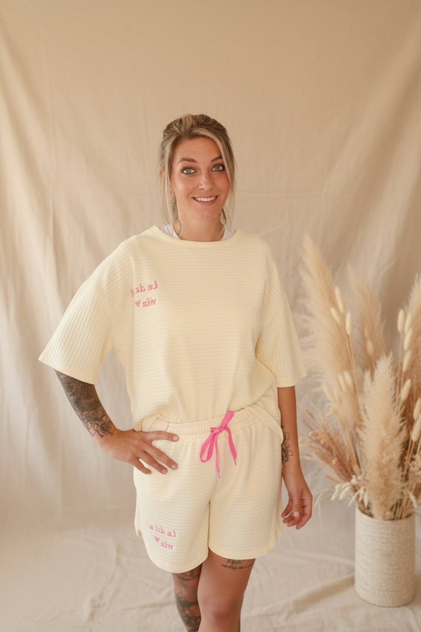 Boho-Luxe Creme-Set aus geripptem Baumwollstoff mit rosa Schriftzug.