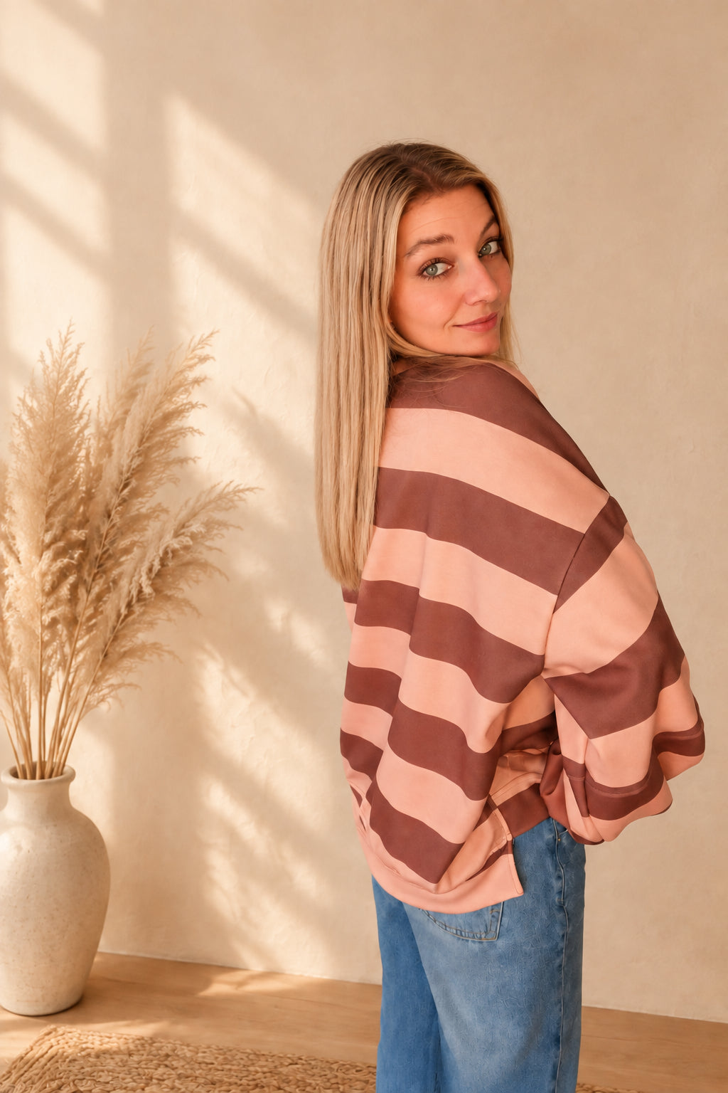 Schräge Rückansicht des gestreiften Damen-Sweatshirts in Rosa und Braun mit überschnittenen Schultern.
