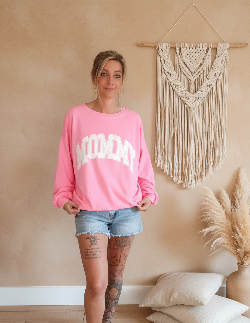 Boho-Luxe Look: Rosa Sweatshirt mit weißem Print und Jeansshorts.