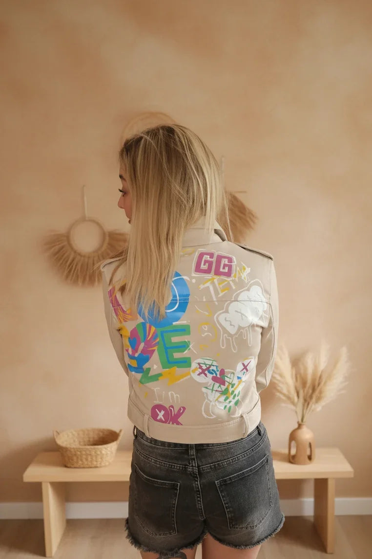 Boho-Luxe Damenjacke aus beigem Stoff mit farbenfrohem Graffiti-Print auf dem Rücken.