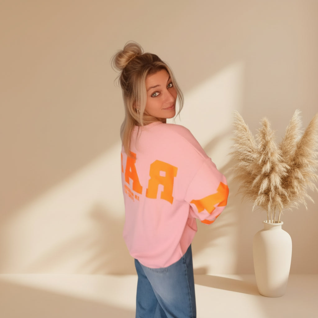 Rosa Damen-Sweatshirt mit orangefarbenem PARADISE-Print in seitlicher Rückansicht, lässig zu Jeans gestylt