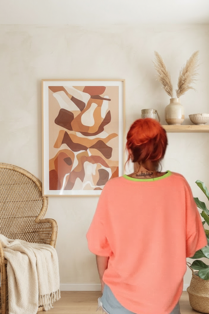 Boho-Luxe Style: Frau in korallenfarbenem T-Shirt vor abstrakter Wandkunst.