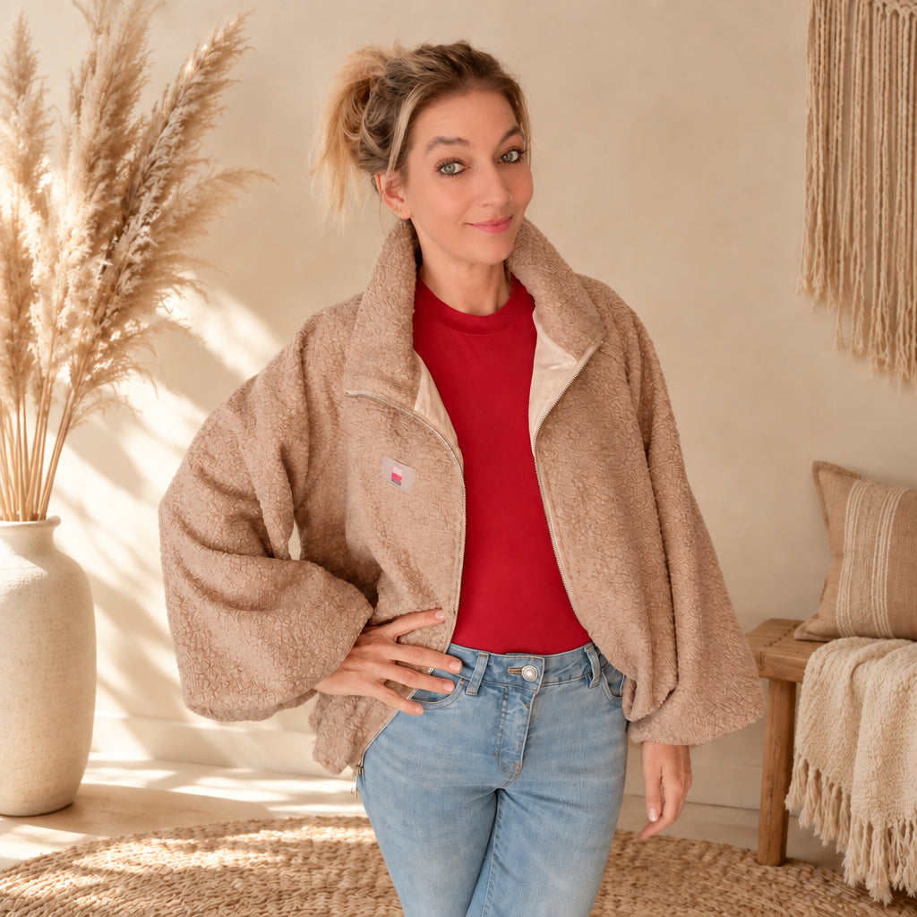 Hellbeige Damen-Teddyjacke offen über einem roten Oberteil, Frontansicht