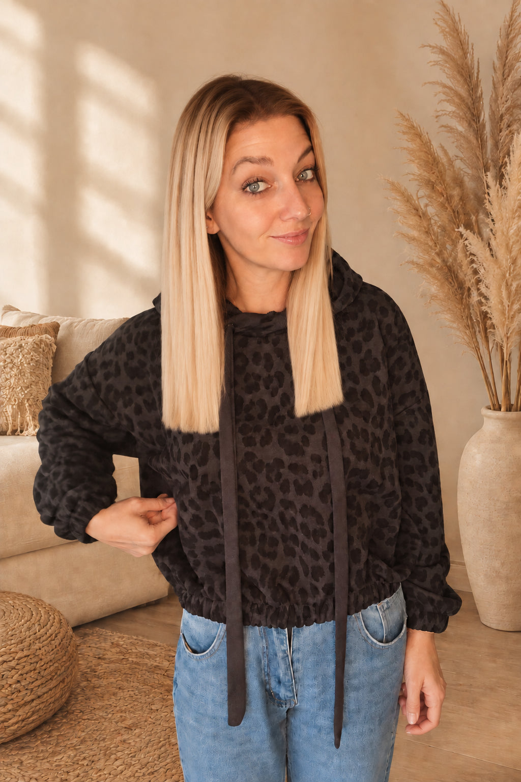 Dunkler Damen-Leo-Hoodie mit Kapuze und langen Bindebändern, Vorderansicht mit seitlich angehobenem Stoff.