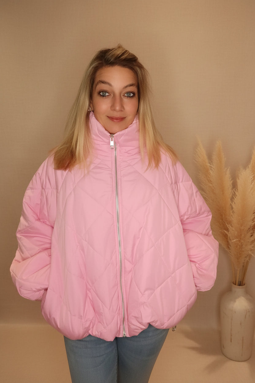 Frau in einer gesteppten, rosa Boho-Luxe Daunenjacke aus glänzendem Material