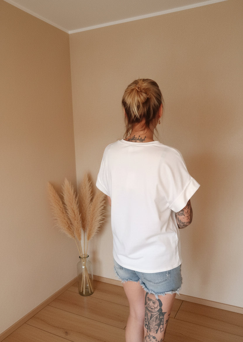 Boho-Luxe Look: Weißes Baumwoll-T-Shirt und Denim-Shorts in hellem Interieur.