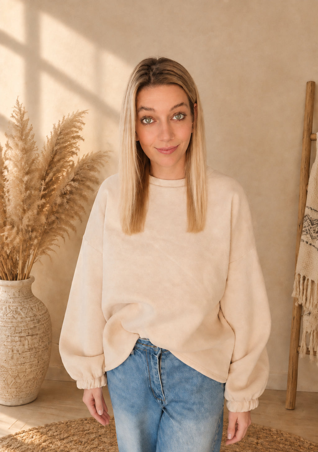 Damen-Sweatshirt in Creme mit weiten Ärmeln und gerafften Ärmelabschlüssen, vorne teilweise in die Jeans gesteckt.