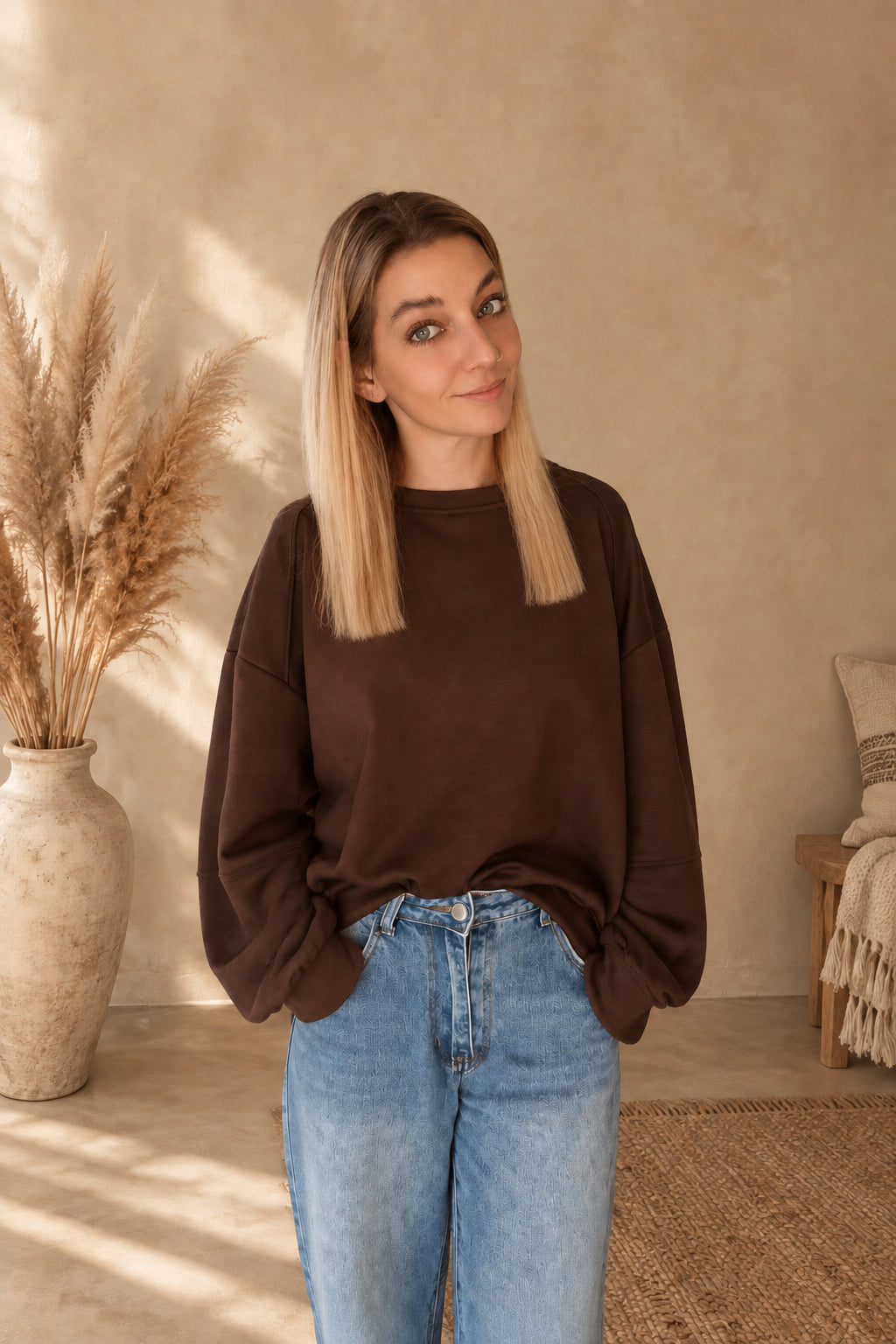 Dunkelbraunes Damen-Sweatshirt mit Rundhalsausschnitt, vorne in eine blaue Jeans gesteckt, am Model mit Händen in den Jeanstaschen.