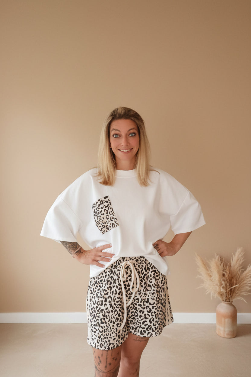 Boho-Luxe Ensemble: Weißes Oversize-Shirt mit Leopardenprint-Tasche und passende Shorts.