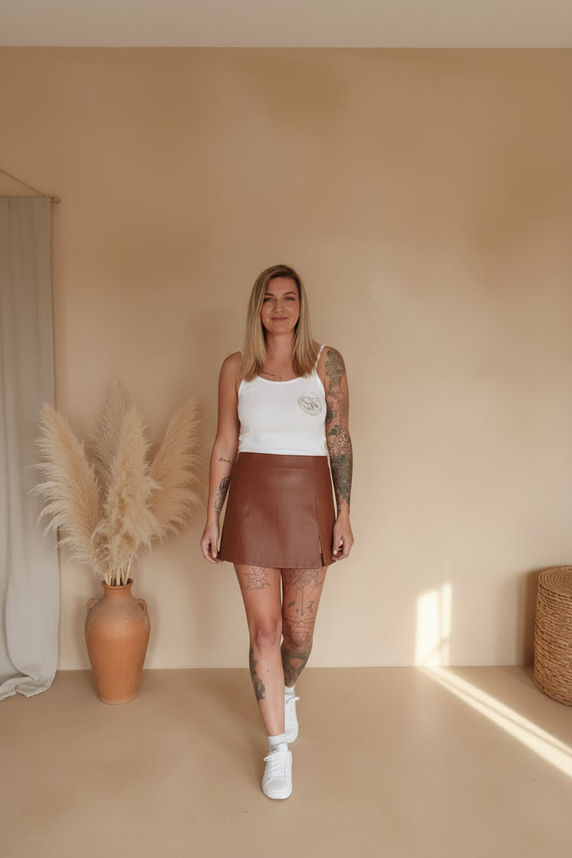 Boho-Luxe Outfit: Eleganter brauner Kunstleder-Minirock kombiniert mit weißem Top.