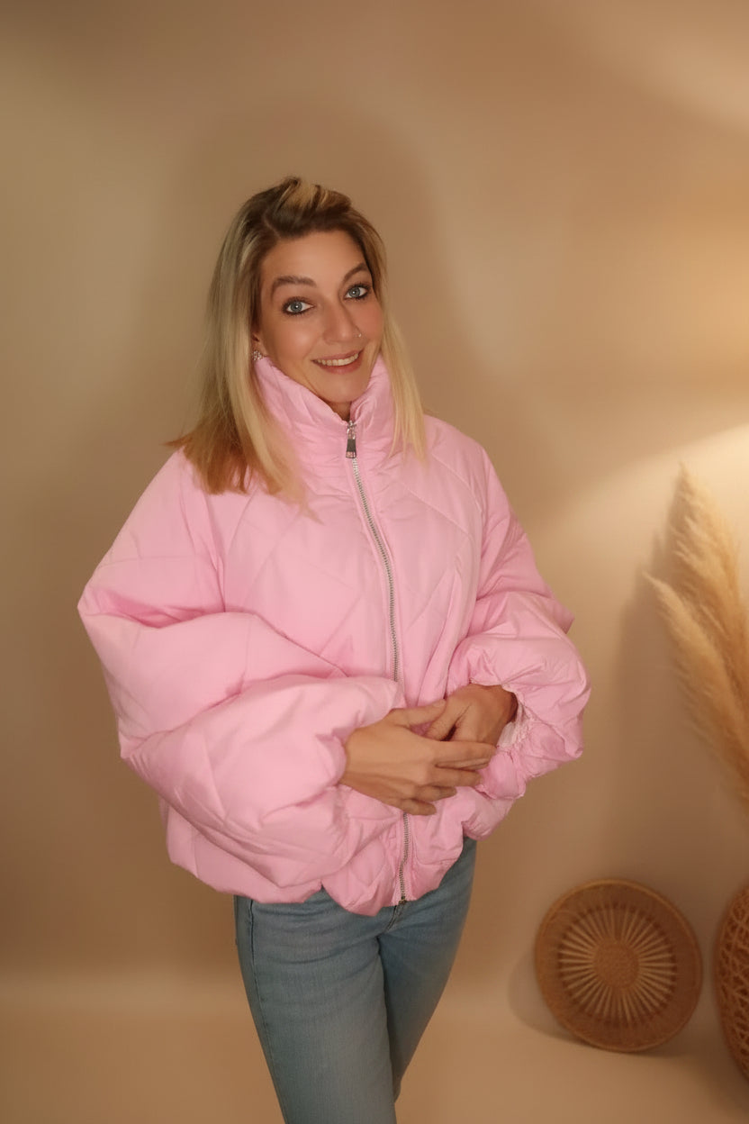 Frau in einer rosa Steppjacke aus glänzendem Material im Boho-Luxe Stil