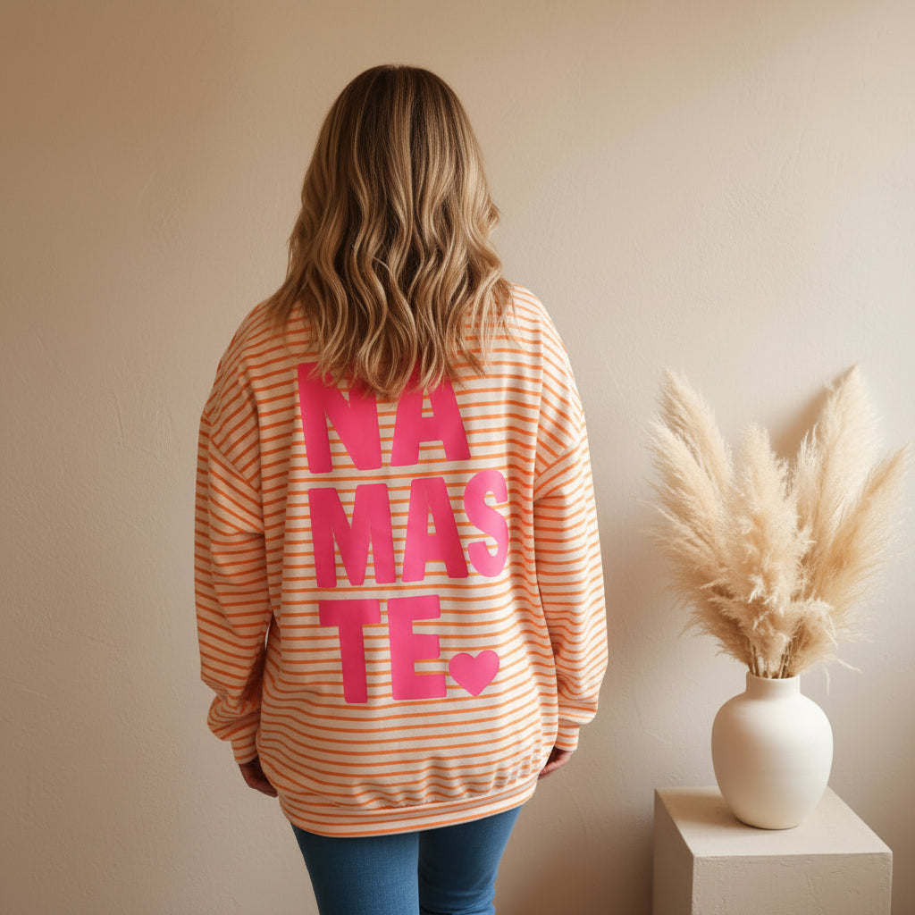 Detailansicht der Rückseite des peach-weiß gestreiften Sweatshirts mit großem pinkem NAMASTE-Schriftzug