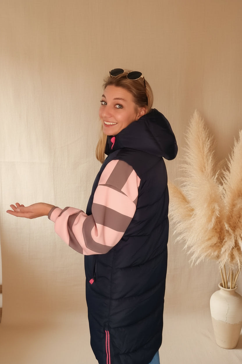 Frau in dunkelblauer Boho-Luxe Steppjacke mit rosa-grauen gestreiften Ärmeln aus glänzendem Material