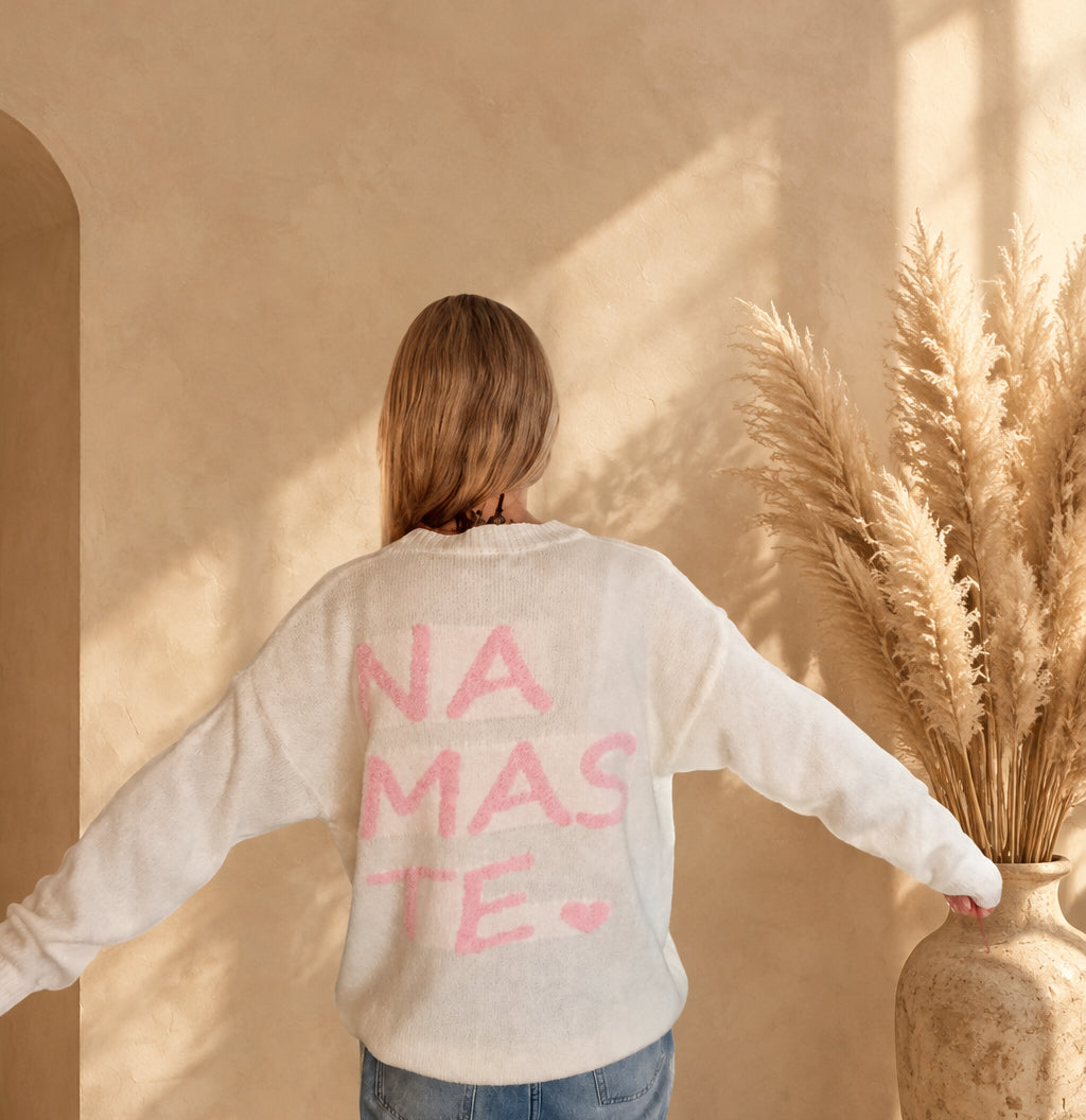 Rückansicht des cremeweißen Namasté-Pullovers, am Model mit ausgestreckten Armen und rosa Rückenprint.