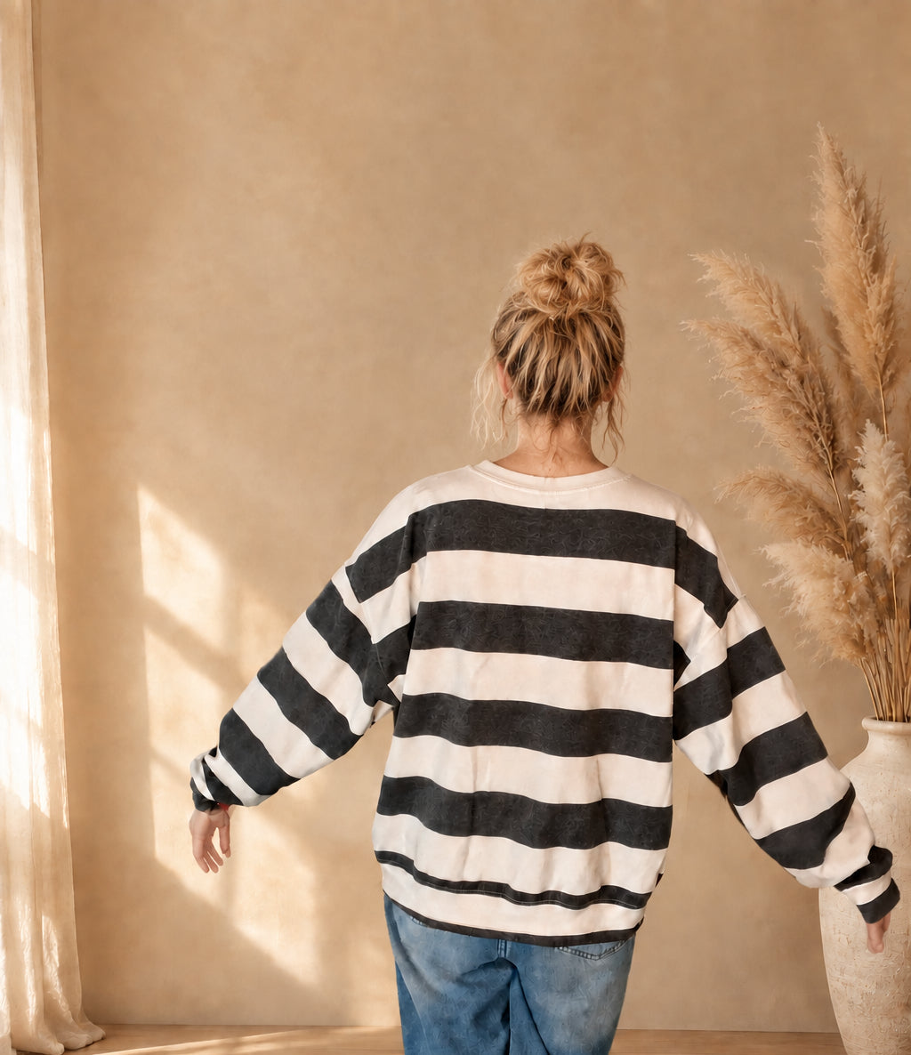 Gestreiftes Damen-Sweatshirt von hinten mit leicht ausgestreckten Armen, weiter Schnitt und lange Ärmel sichtbar.