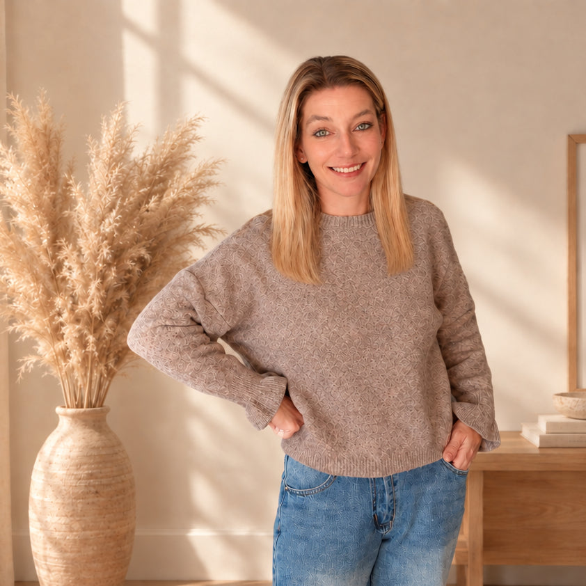 Taupefarbener Damenpullover mit Rundhalsausschnitt und geripptem Saum am Model, dazu blaue Jeans.