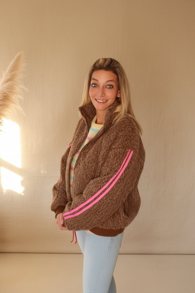 Damen Jacke braun mit pinken Streifen, lässige Pose, natürliches Sonnenlicht