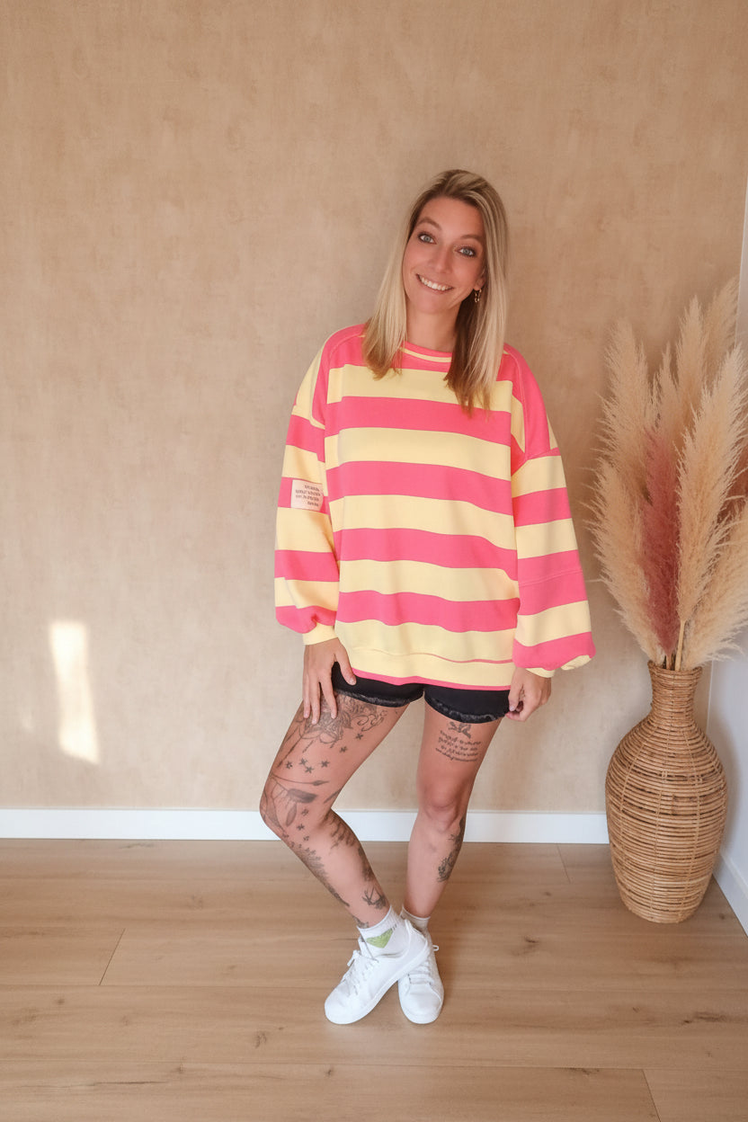 Boho-Luxe Damenmode: Gestreifter Oversize-Sweatshirt in Pink und Gelb aus weichem Baumwollstoff.