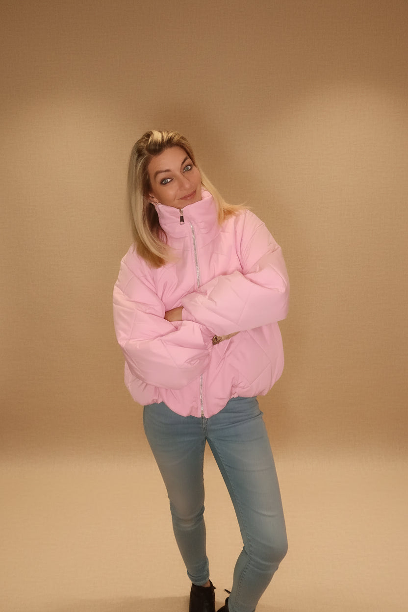 Frau in rosa gesteppter Boho-Luxe Daunenjacke und hellblauer Jeans