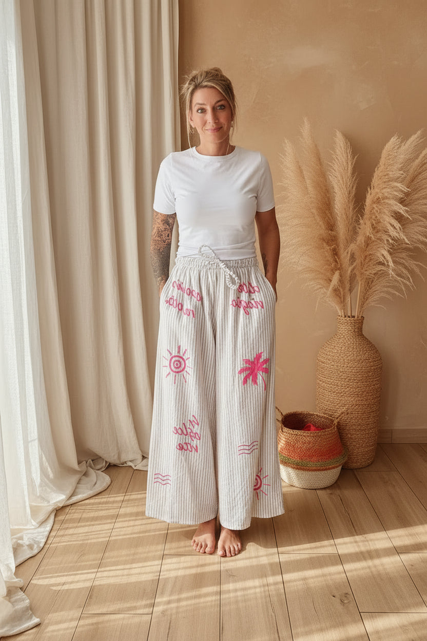 Boho-Luxe weiße Leinenhose mit pinken Stickereien und Streifenmuster.