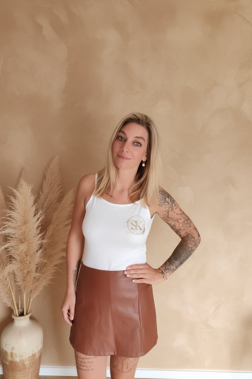 Boho-Luxe Look: Weißes Tanktop aus Baumwolle und brauner Lederrock für Damen.