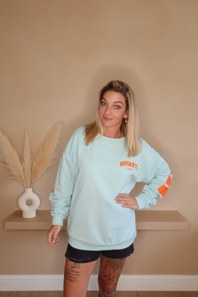 Namaste Oversized Pullover Damen – Frontansicht mit orangem Brustprint, Lifestyle-Shot