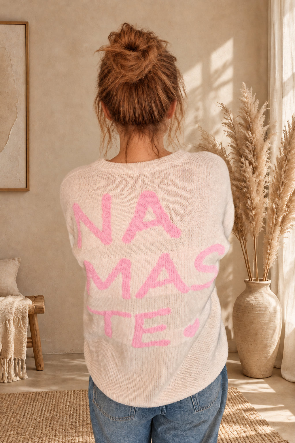 Cremeweißer Damen-Strickpullover mit großem rosa Namasté-Rückenprint und Herz, am Model mit blauer Jeans.