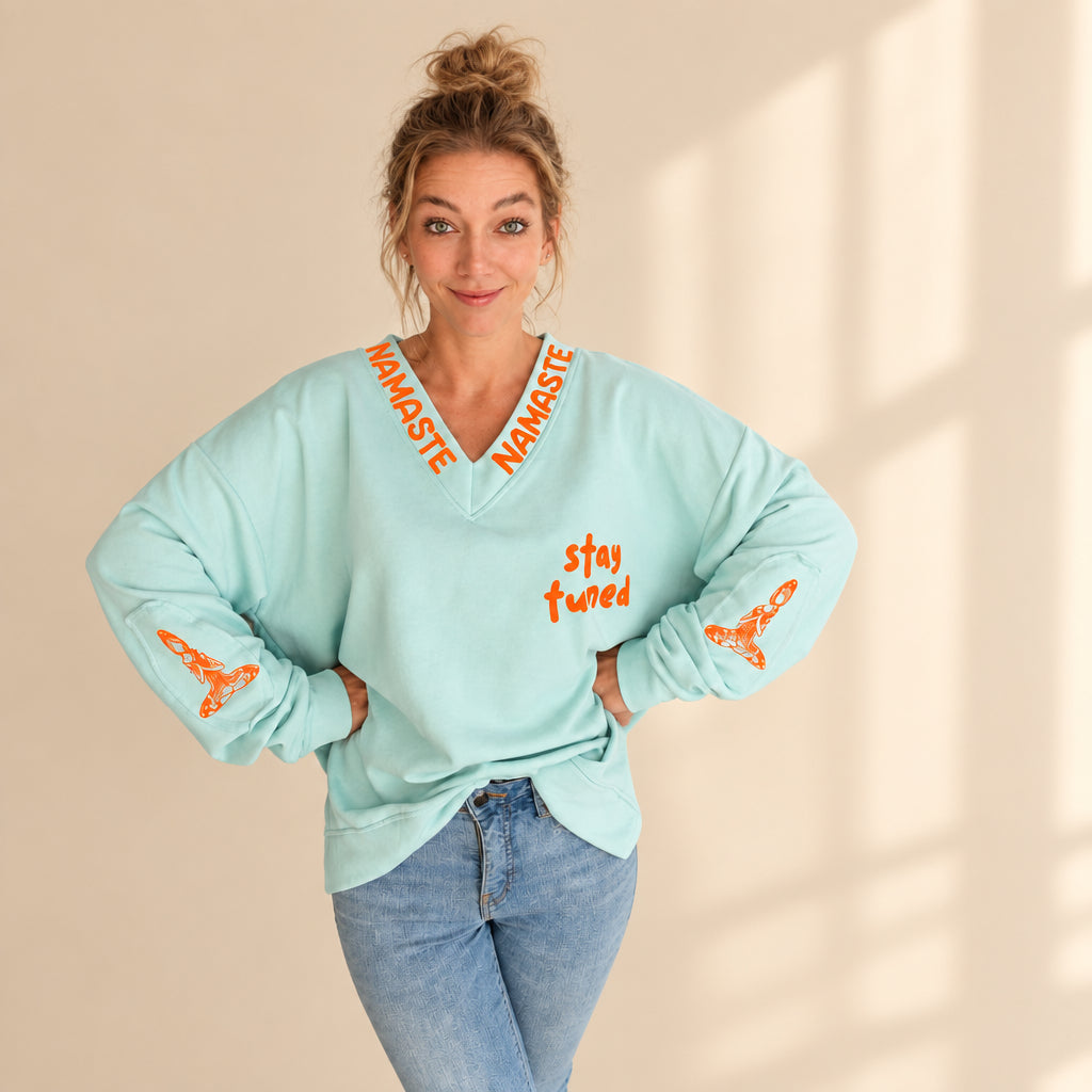 Mintfarbener Damenpullover mit orangefarbenem Stay-tuned-Print und Prints an beiden Ärmeln