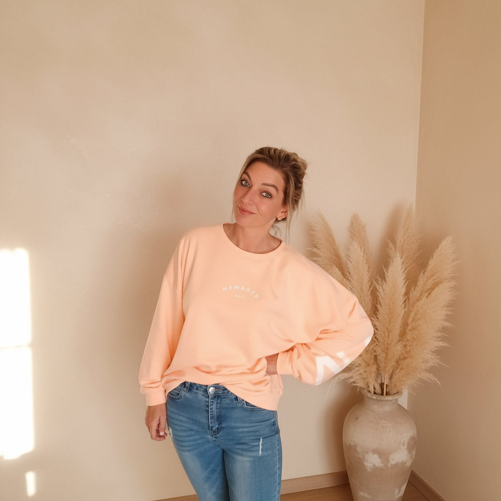 Damen trägt peachfarbenes Oversize Sweatshirt mit weißem Print, Styling für Yoga und Freizeit