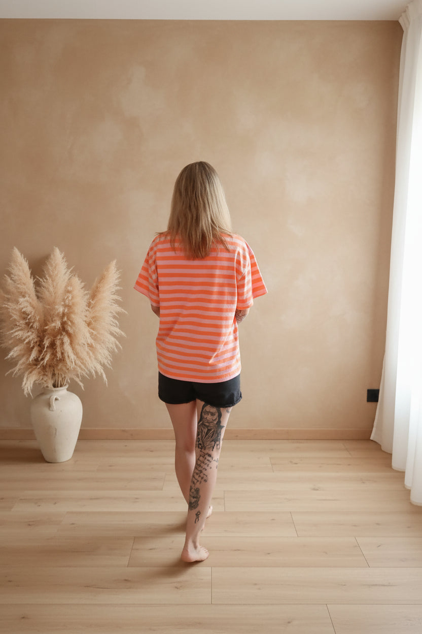 Boho-Luxe Outfit: Orange-gestreiftes Baumwoll-T-Shirt und schwarze Shorts.