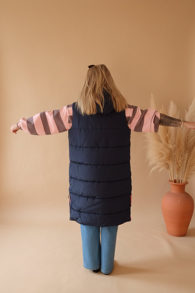 Boho-Luxe lange Steppweste in Dunkelblau über einem gestreiften Oberteil und Jeans.
