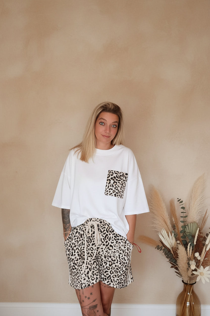 Boho-Luxe Outfit: Weißes Baumwoll-T-Shirt mit Leopardenprint-Tasche und passenden Shorts.