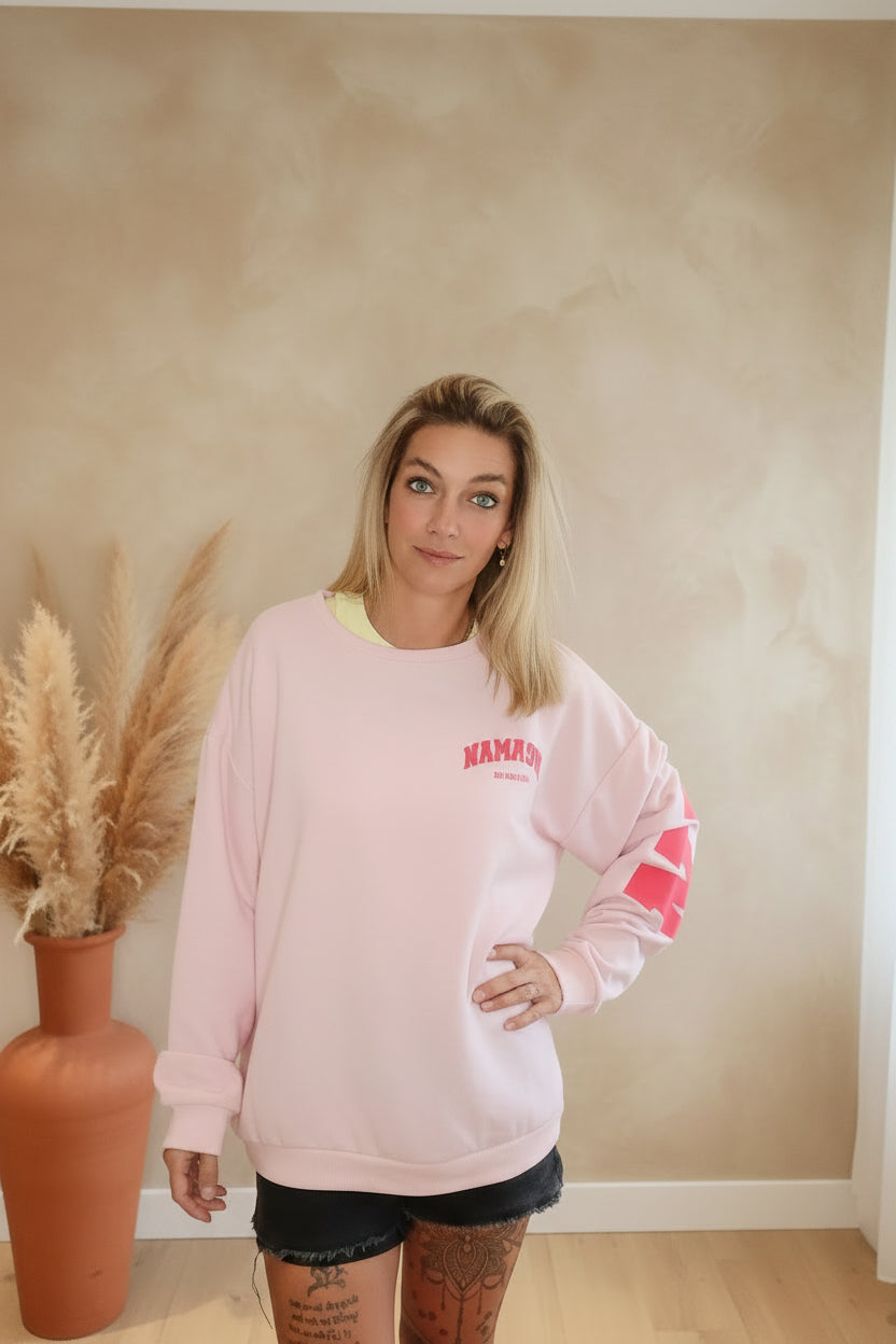 Namasté Oversize Sweater Pink – Frontansicht Hand an Hüfte, Ärmel-Print sichtbar, Boho-Ambiente