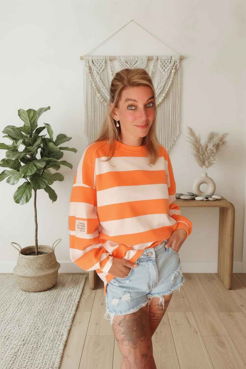 Boho-Luxe Look: Damen Sweatshirt mit orange-weißen Streifen aus weichem Stoff und Denim-Shorts.