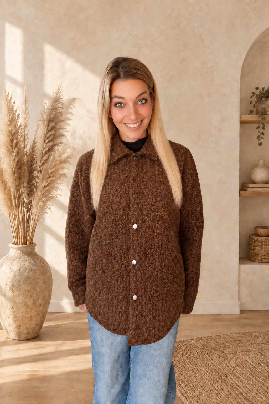 Frontansicht der geschlossenen braunen Damenjacke mit Kragen und langen Ärmeln, am Model mit Händen hinter dem Körper.