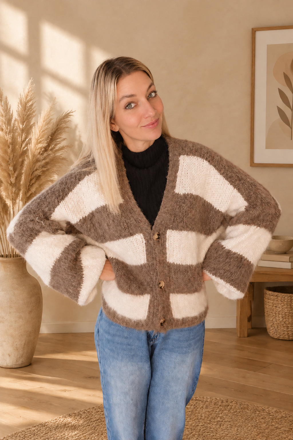 Taupe-creme gestreifter Damen-Cardigan mit weiten Ärmeln und Knöpfen, am Model mit Händen an der Hüfte.