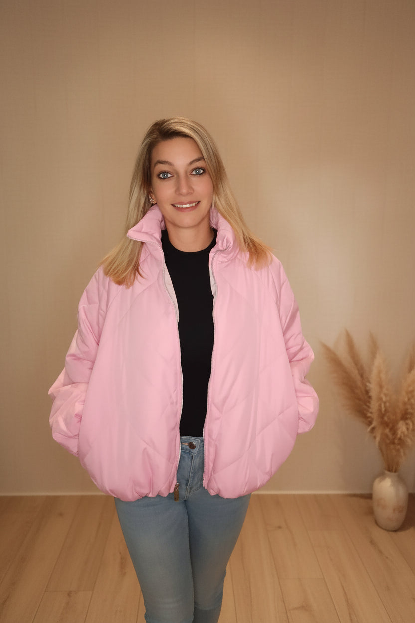 Frau in eine rosa gesteppten Daunenjacke aus glänzendem Material und hellblauen Jeans