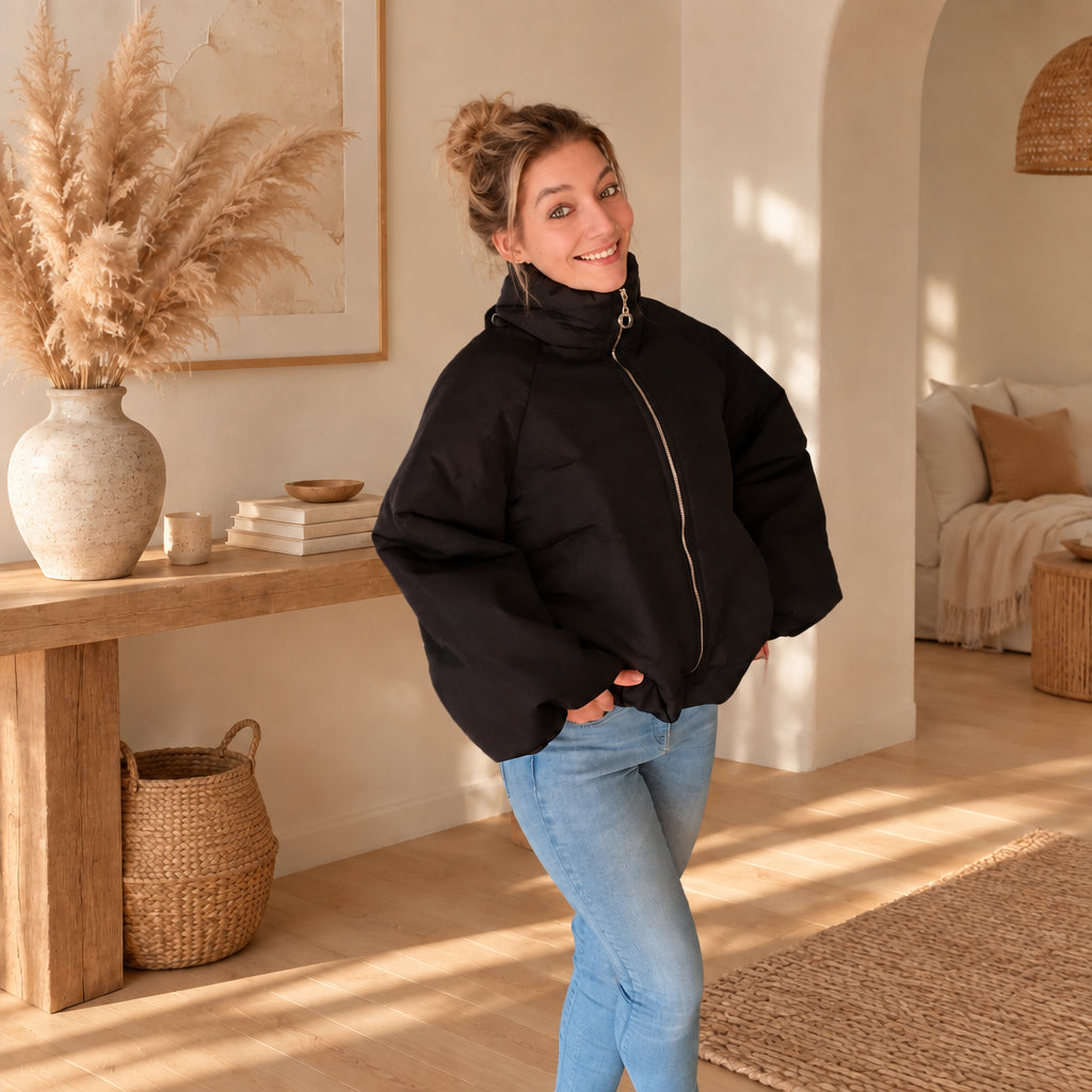 Schwarze Damenjacke mit hohem Stehkragen, leicht schräge Frontansicht mit Händen in den Taschen