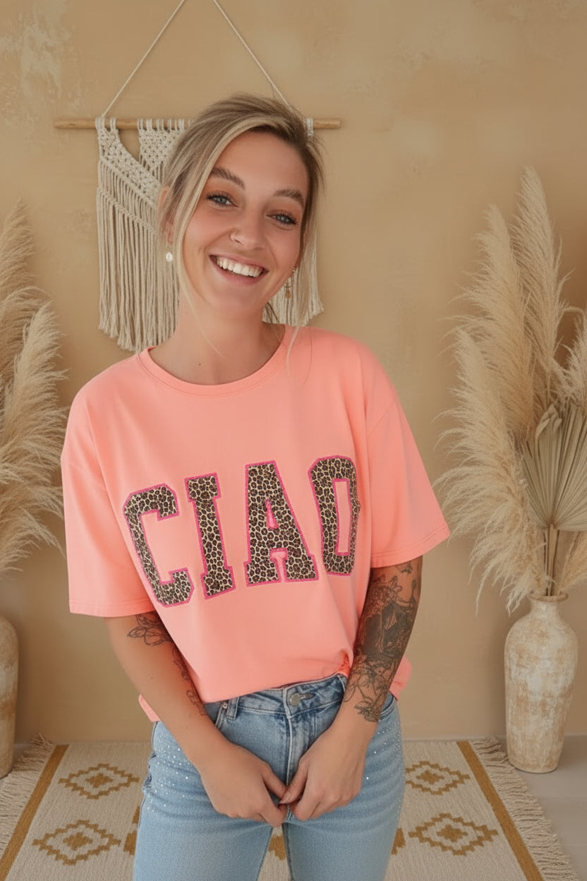 Lachsfarbenes Boho-Luxe T-Shirt mit Leopardenmuster-Aufdruck und hellblauen Jeans.