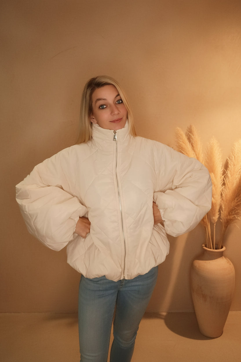 Frau in einer cremeweißen, gesteppten Boho-Luxe Steppjacke aus glänzendem Material.