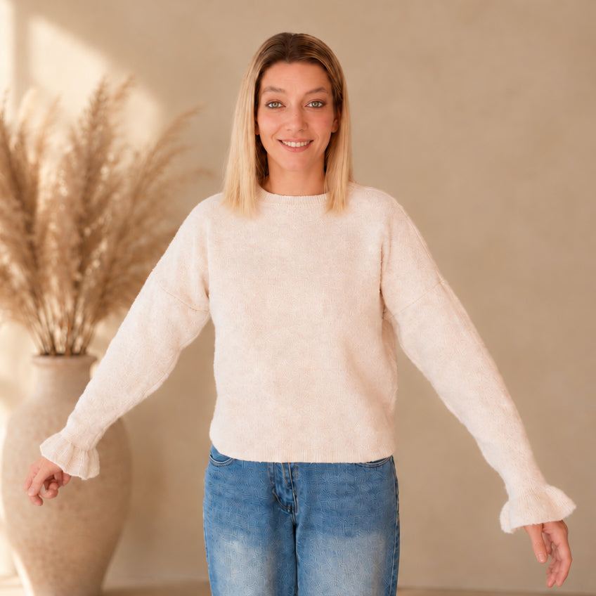 Heller Damenpullover von vorn am Model, mit ausgestreckten Armen und leicht ausgestellten Ärmelabschlüssen.