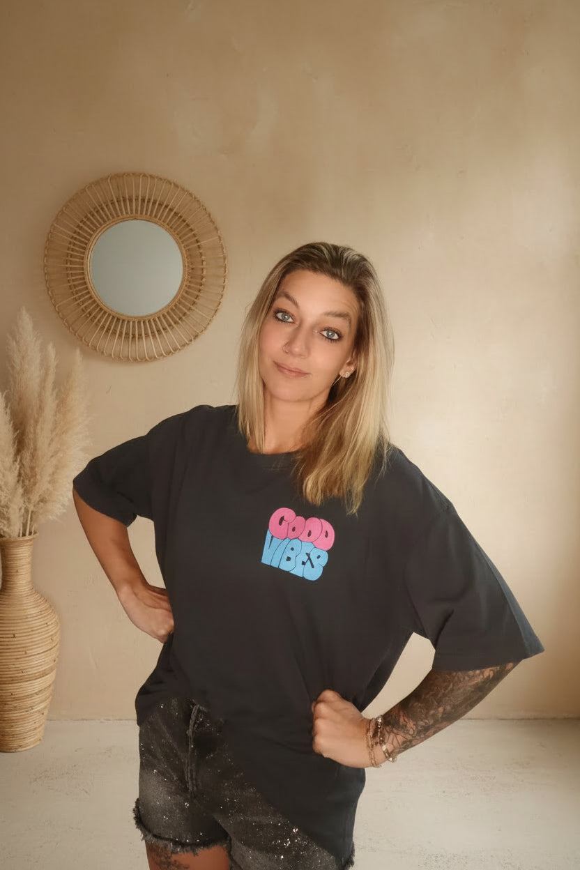 Good Vibes Shirt Damen Anthrazit – Frontansicht Hände in Hüften lächelndes Model Boho Wand