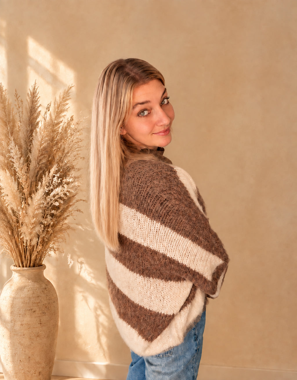 Seitliche Rückansicht des Damen-Strickcardigans mit breiten Streifen in Taupe-Creme, Blick über die Schulter.