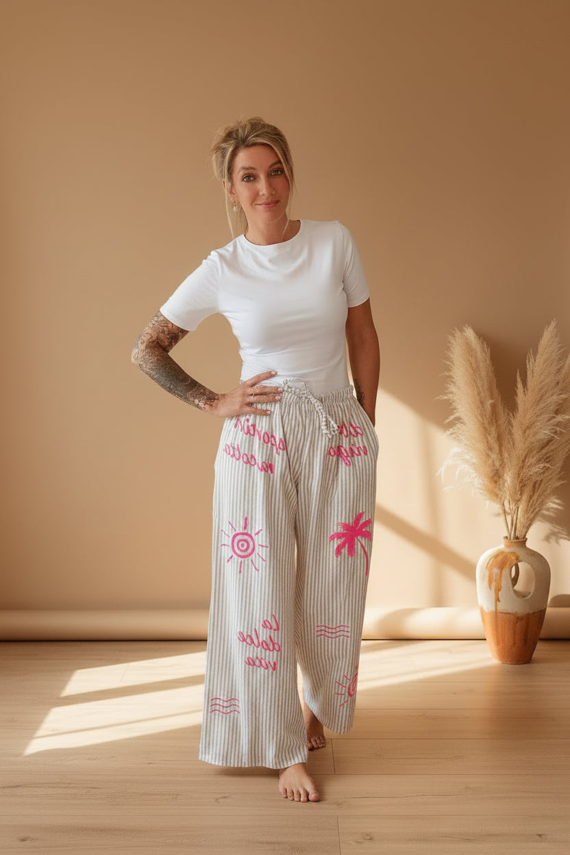 Boho-Luxe gestreifte Palazzo-Hose aus Baumwolle mit pinken Akzenten an einer Frau.