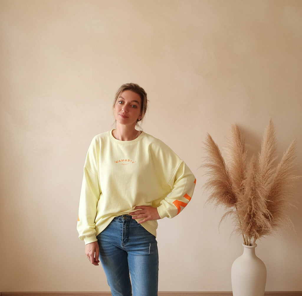 Namasté Oversize Sweatshirt Damen Pastellgelb – Frontansicht Hand in Hüfte seitlicher Blick Neonorange Ärmelprint