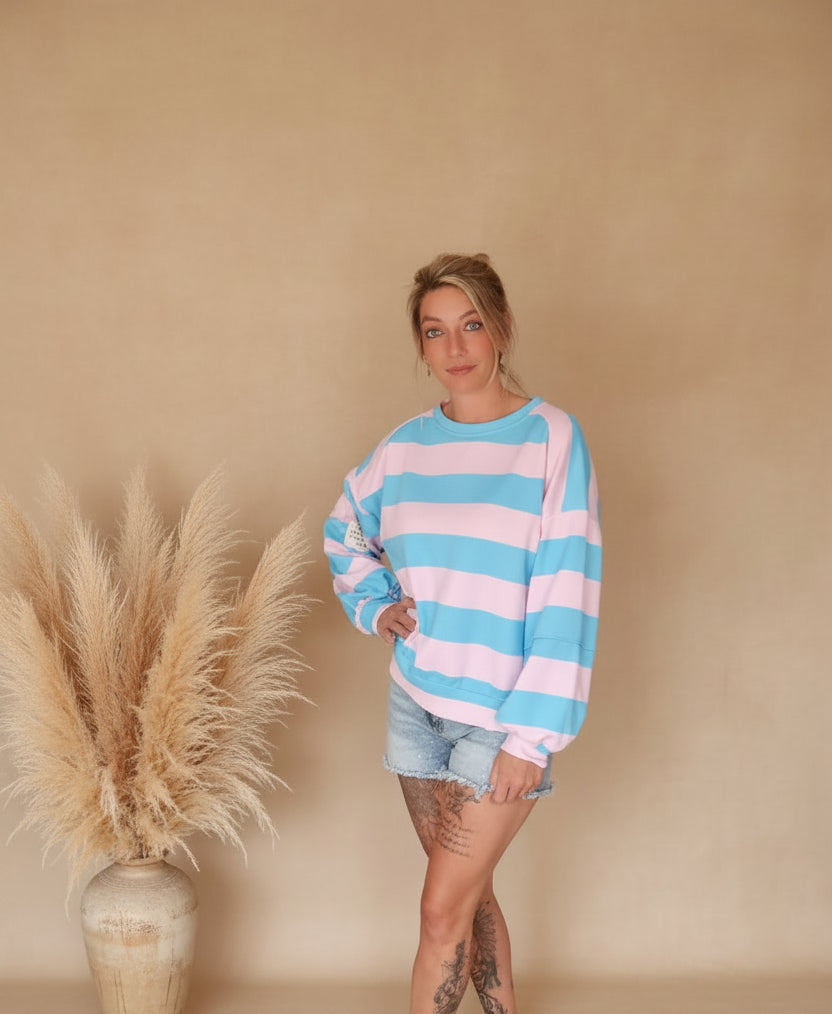 Boho-Luxe Look: Damen Pullover mit rosa-blauen Streifen aus weichem Stoff und Jeansshorts.