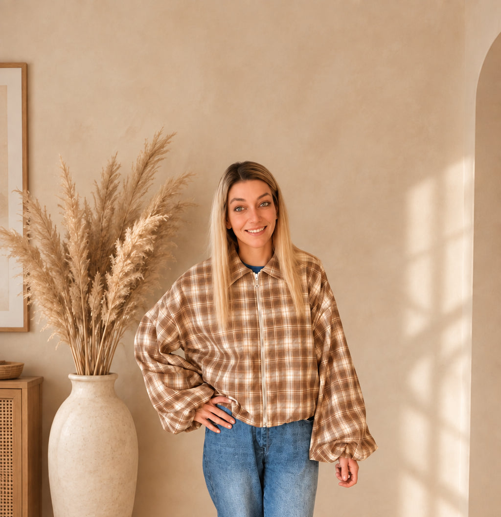 Kurze karierte Damenjacke in Braun und Creme mit geschlossenem Reißverschluss, zu blauer Jeans kombiniert.